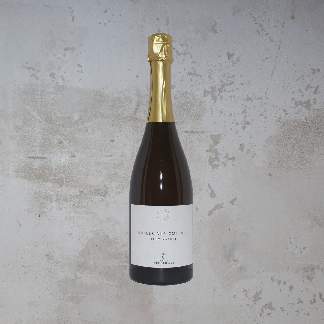 Flasche Domaine Apostolidi Bulles des Coteaux 2019 BIO. Die stilvolle Flasche zeigt ein elegantes Etikett mit moderner Schrift und einem ansprechenden Design, das die spritzigen Aromen und die biologisch angebaute Traube dieses griechischen Schaumweins hervorhebt.