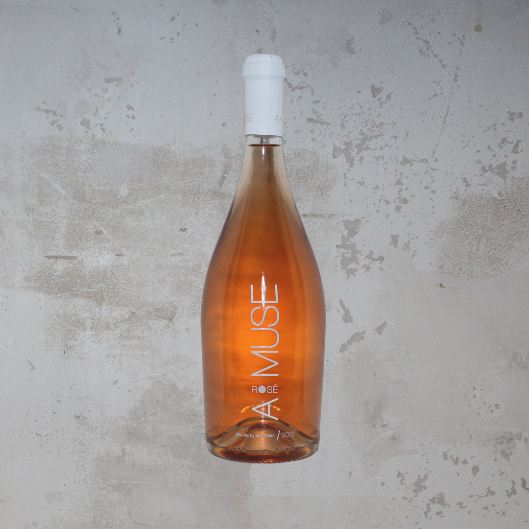 Flasche Muses Estate Amuse 2022 Rosé. Die elegante Flasche präsentiert ein ansprechendes Etikett mit stilvoller Schrift und einem modernen Design, das die fruchtigen Aromen und die handwerkliche Herstellung dieses griechischen Roséweins hervorhebt.