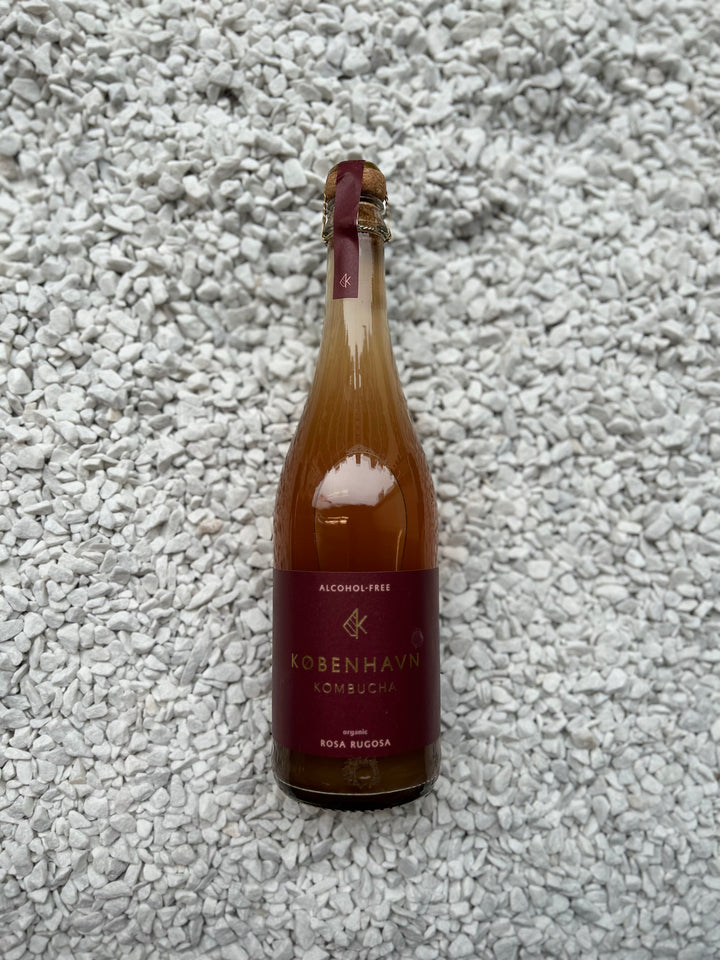 Flasche Rosa Rugosa 0.00% von København Kombucha. Die elegante Flasche trägt ein rosa Etikett, das den blumigen und alkoholfreien Charakter des erfrischenden Kombucha-Getränks hervorhebt.