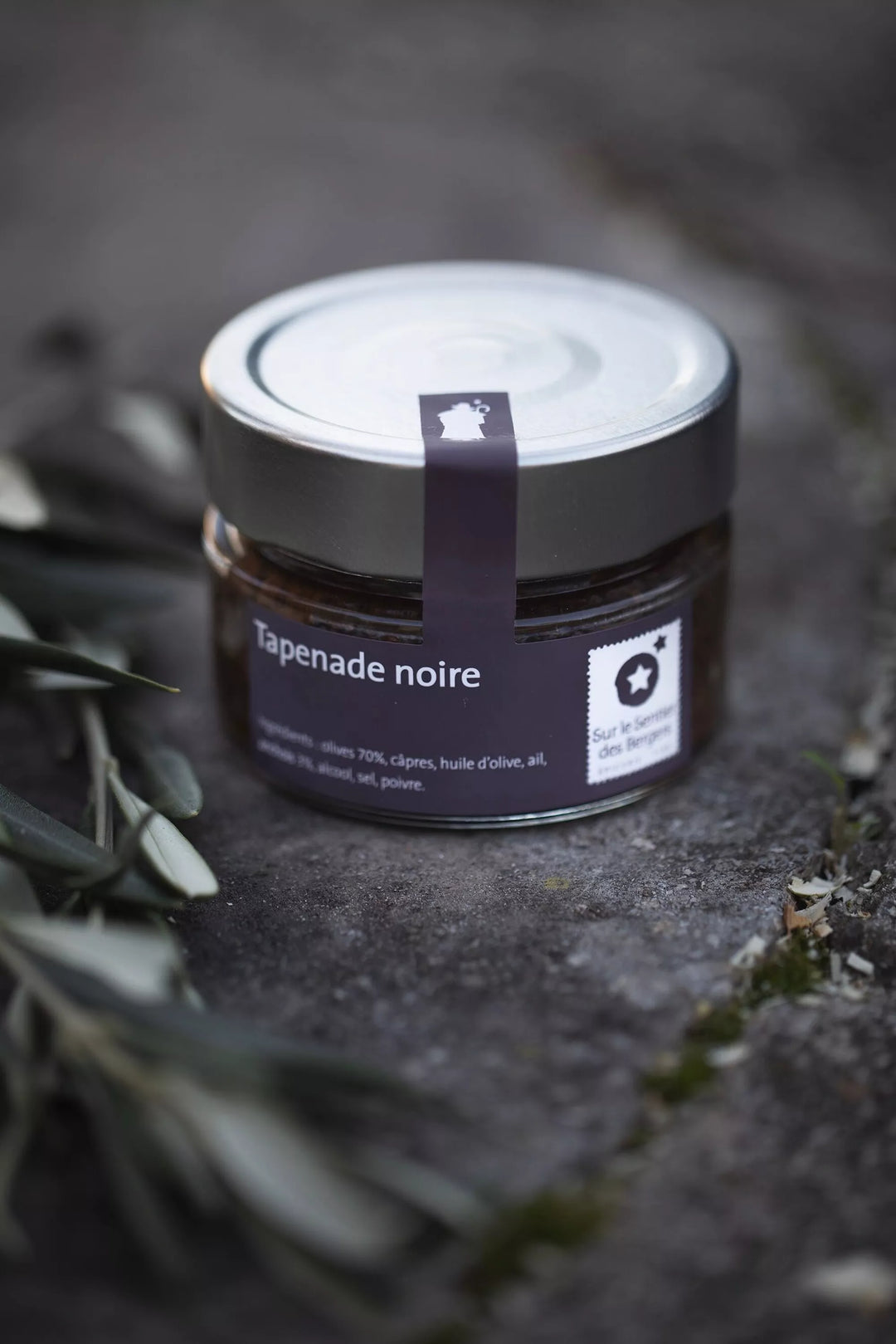 Schwarze Tapenade von Sur le Sentier des Bergers, Feinkost, cremige Paste aus schwarzen Oliven auf weißem Teller